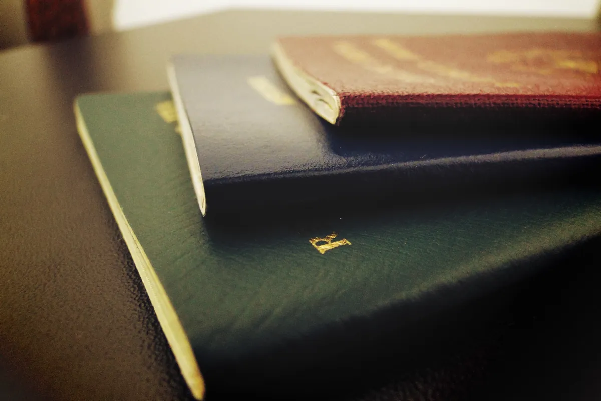 Closed passports stacked on a dark table, ready for an identity check