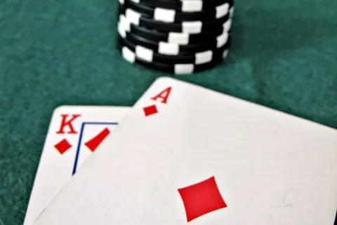 King and ace of diamonds on green felt beside a stack of black chips