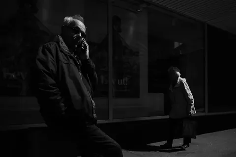 Man talking on a mobile phone on a shaded city street