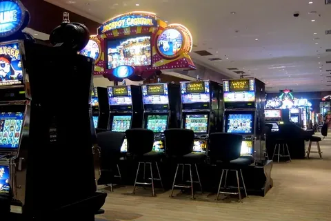 Rows of slot machines with stools across a casino floor
